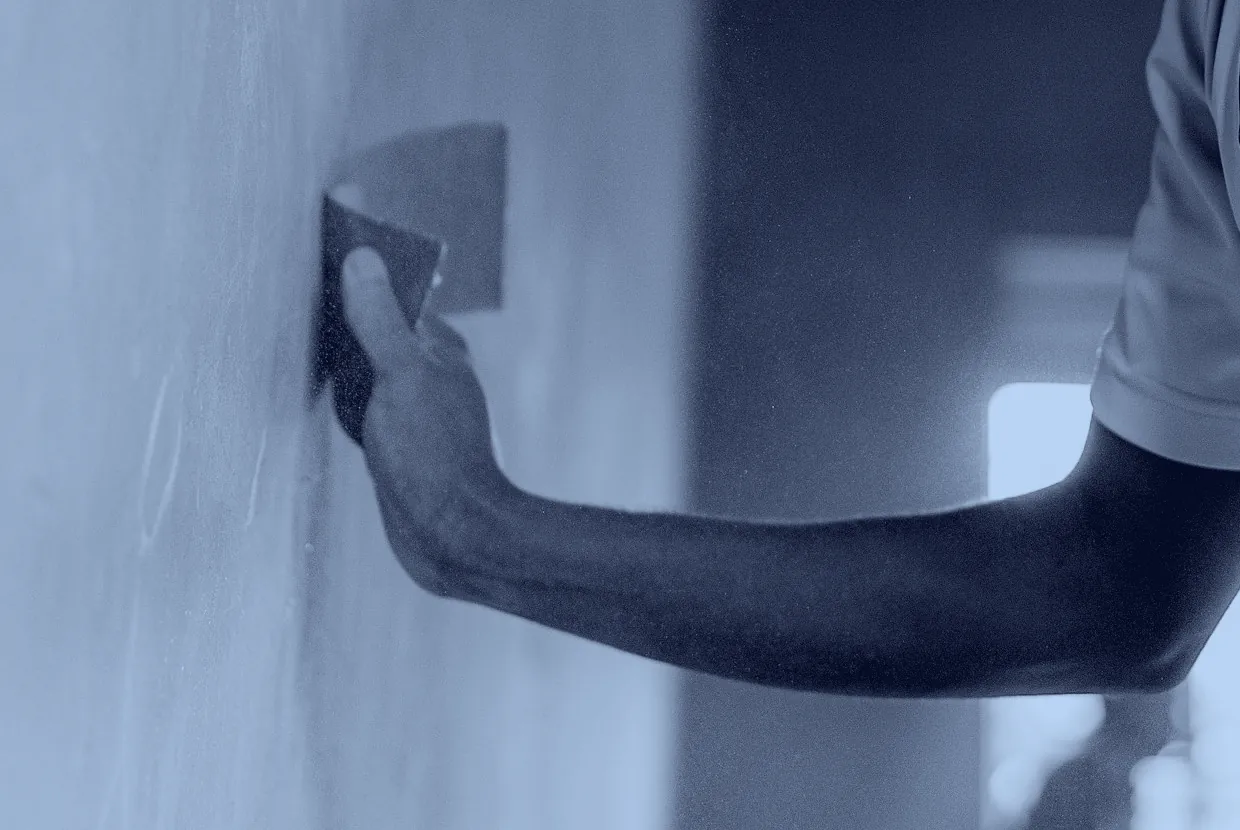 Un operario alisando el enlucido de una pared con la llana